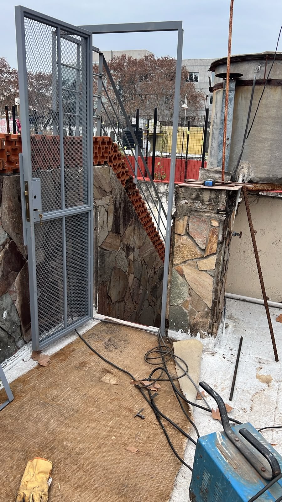 Puerta de hierro exterior con malla de metal desplegado y cerradura de seguridad colocada
