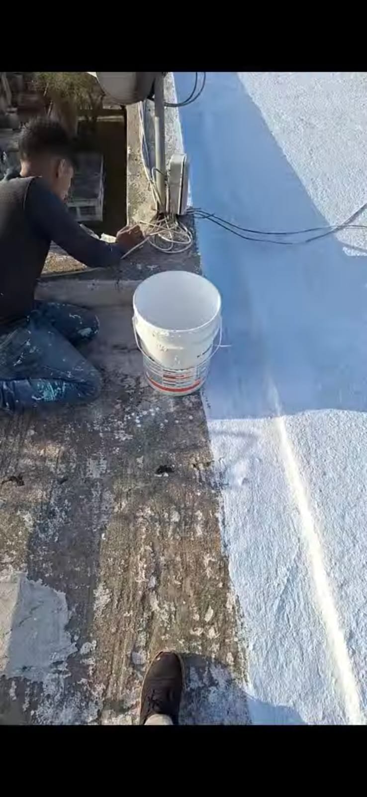 Pintor aplicando recubrimiento impermeabilizante blanco sobre losa de terraza exterior
